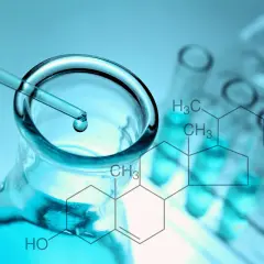 Pipeta z kroplą płynu nad kolbą, probówki i wzór chemiczny cholesterolu.
