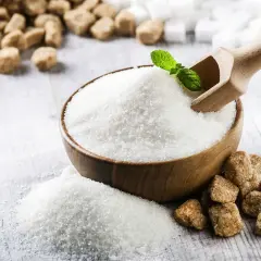 Miska z białym cukrem, drewniana łopatka, liść mięty, cukier brązowy i kostki cukru.