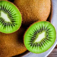 Kiwifruit w misce, przekrojone na pół, ukazujące zielony miąższ z czarnymi pestkami.