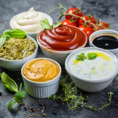 Kilka miseczek z różnymi sosami: pesto, ketchup, majonez, musztarda, sos jogurtowy i ciemny sos.