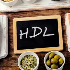 Ryba, łosoś, oliwki, pestki i tabliczka z napisem HDL na drewnianym tle.