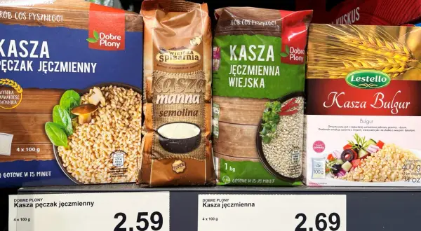 Cztery opakowania kaszy jęczmiennej i kaszy bulgur na półce sklepowej.