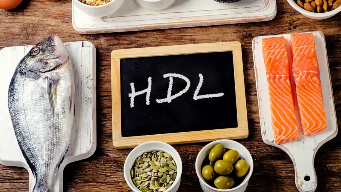 Ryba, łosoś, oliwki, pestki i tabliczka z napisem HDL na drewnianym tle.